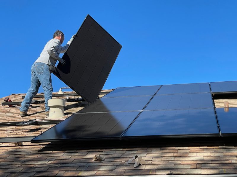 a worker laying down solar panels on top of a house