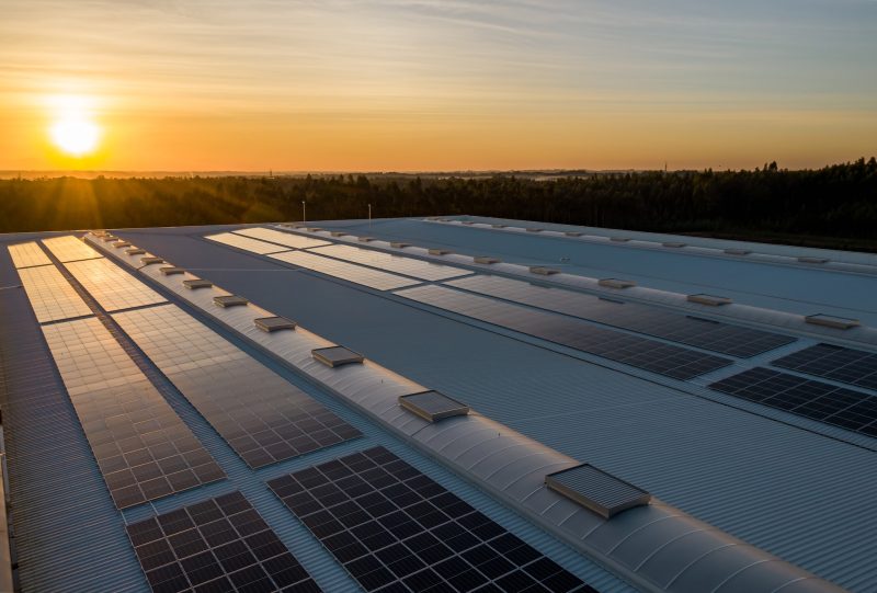 black solar panels on a roof of a big building during a sunset